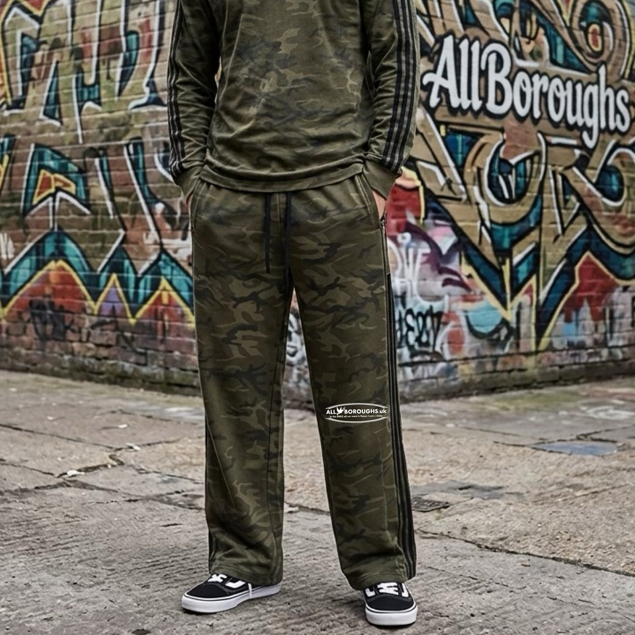 Person wearing a green camo tracksuit with 'All Boroughs' branding in front of a graffiti-covered wall.