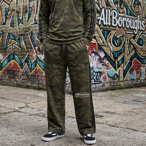 Person wearing a green camo tracksuit with 'All Boroughs' branding in front of a graffiti-covered wall.