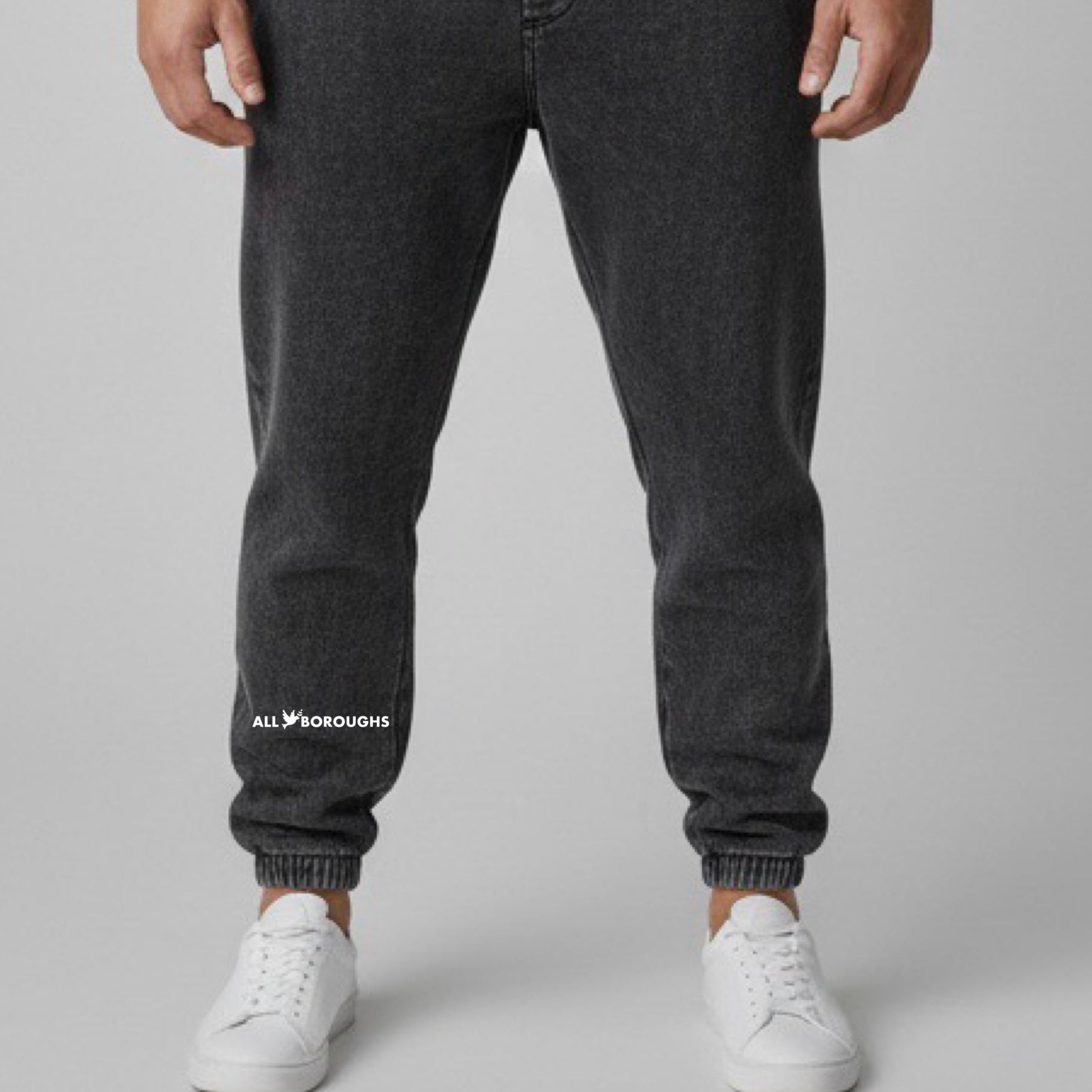 Person wearing black jogger pants with 'All Boroughs' logo on a gray background