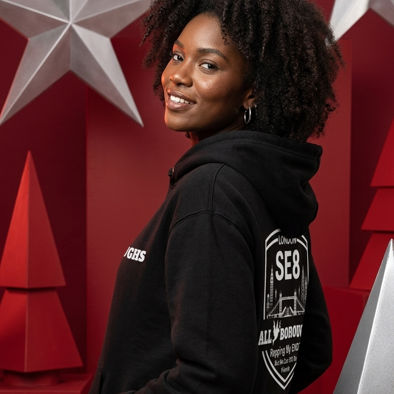 Person wearing a black ALLBOROUGHS hoodie with text and graphics, standing against a red background with star designs.