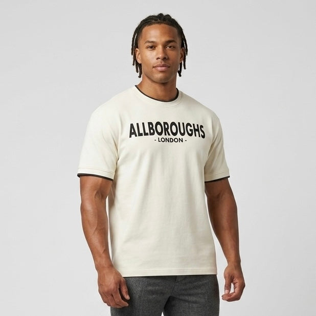 Man wearing a beige t-shirt with 'ALLBOROUGHS LONDON' text on a plain background